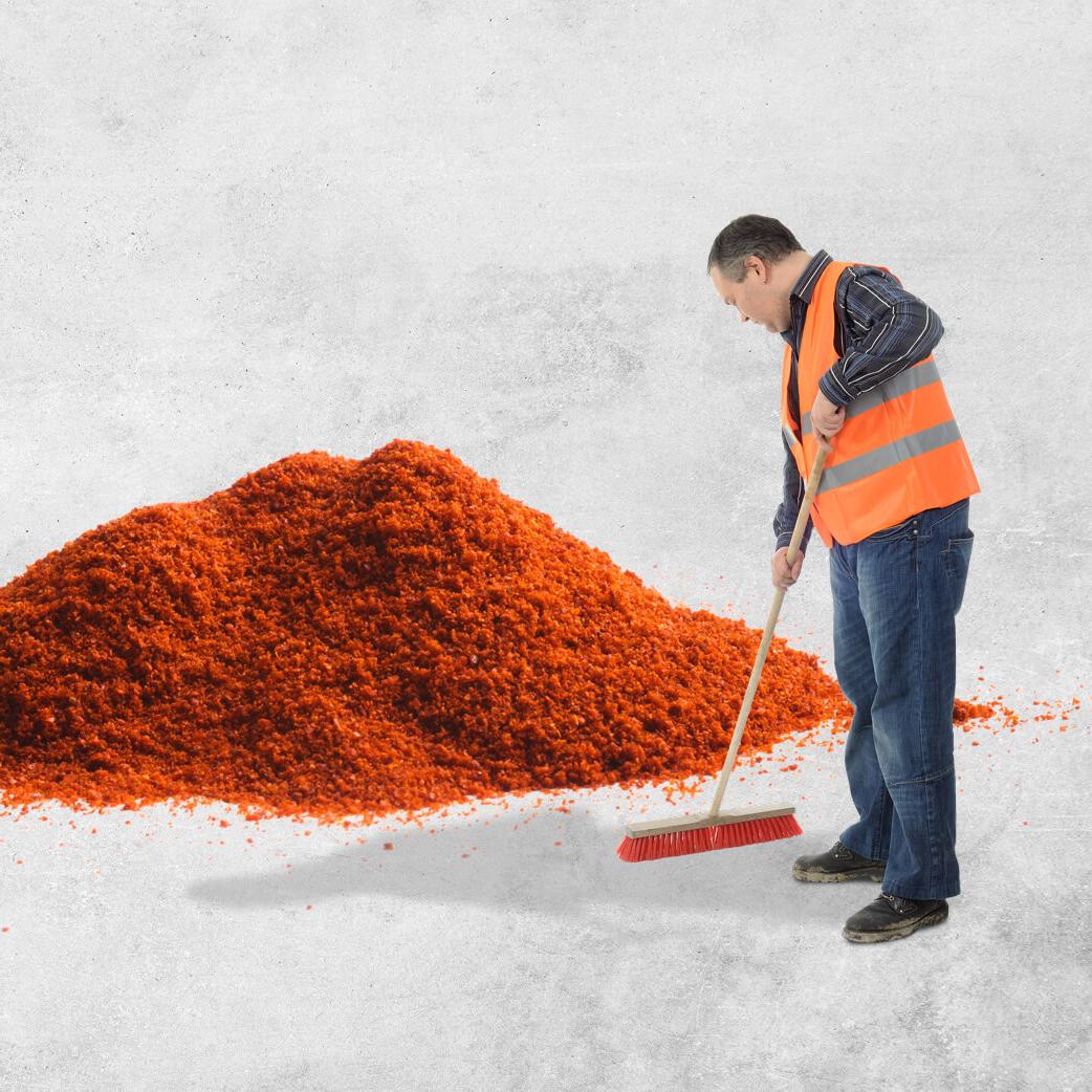 一名男子正在用扫帚清扫一大堆橙色的灰尘
